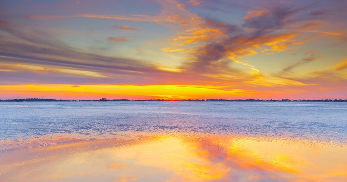 Colores del atardecer se reflejan en el mar y las nubes