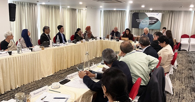 People seated around a table listening to a presentation.