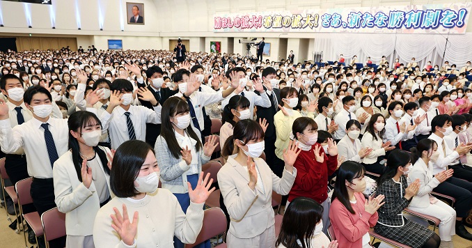 People in a big conference hall clapping and waving their hands.