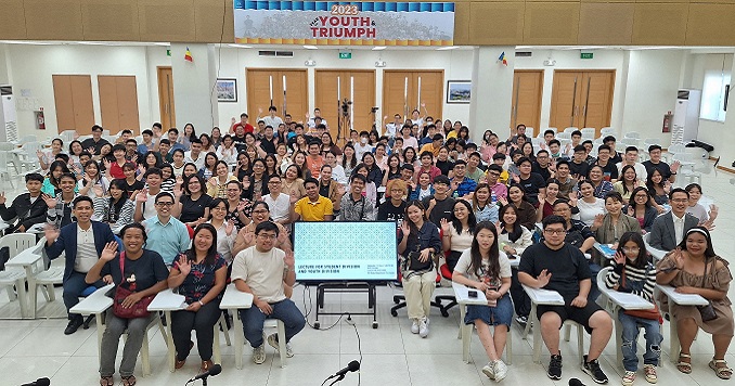 Young people seated in a conference room facing the camera and posing for a group photo.