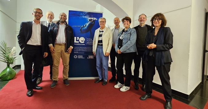 Eight people posing for a group photo in front of an exhibition panel.