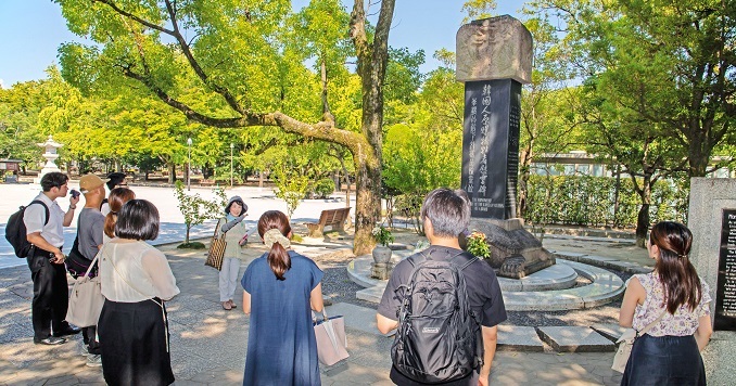 Personas de pie alrededor de un monumento en un parque.