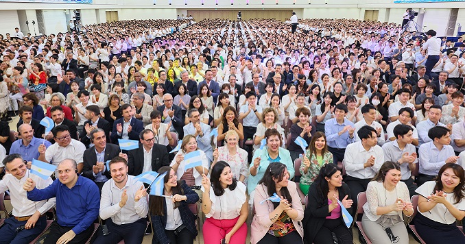 Cientos de personas aplaudiendo reunidas en una gran sala.