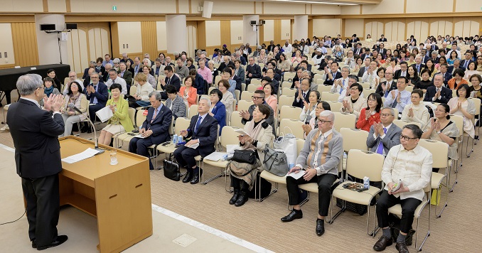 People seated in a conference room listening to a speaker at a podium.