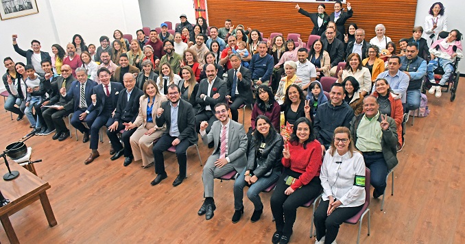 A group of people seated in a hall posing for a photo.