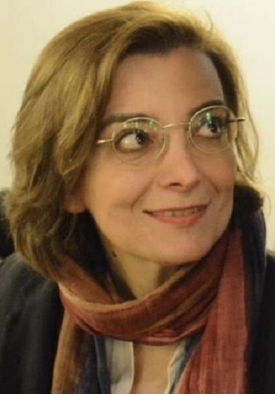 Mujer con gafas, sonríe alzando la mirada.