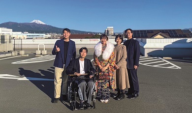 一个家庭与坐轮椅的亲人合影,背景中可见富士山。