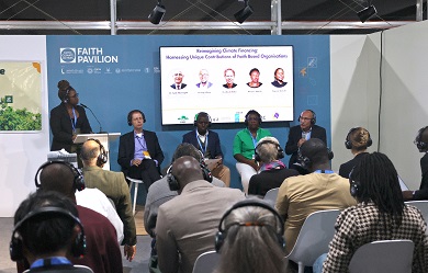 People seated in a room listening to a panel discussion with five speakers on stage. 