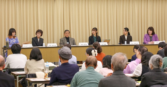 People sitting at a long desk with name plates in front of them.