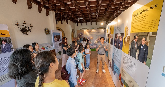 People gathered around exhibition panels listening to a guide.