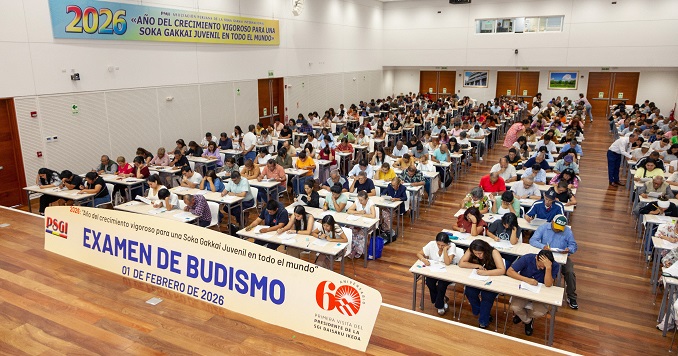 Many people in a hall seated at desks taking exams.