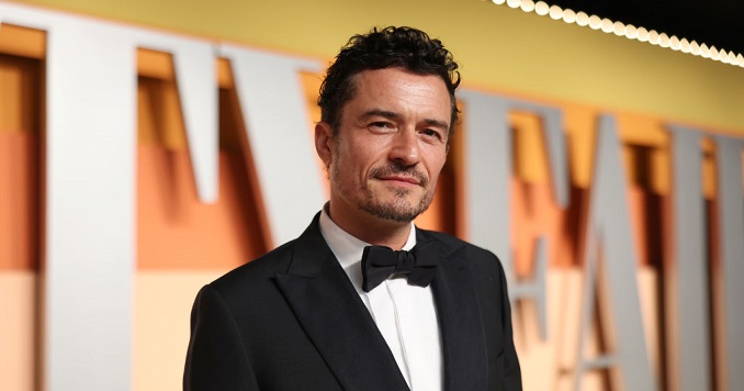 Orlando Bloom in a tuxedo posing for a photo.