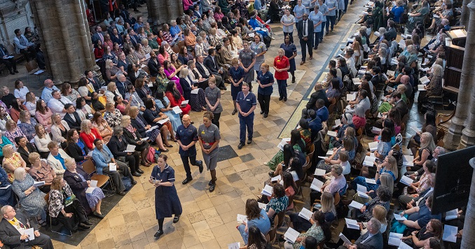 A procession down the aisle of church with an audience watching on both sides of the aisle.