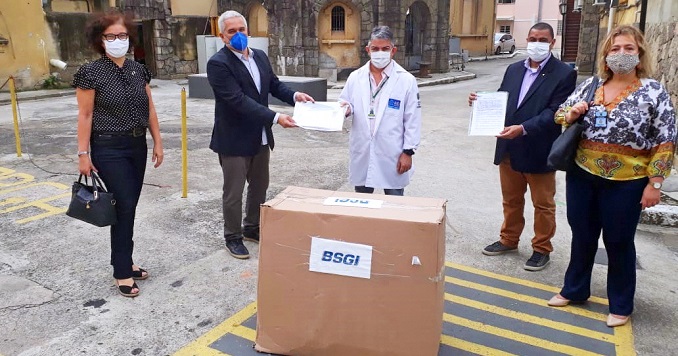 Five people wearing masks outside standing around big cardboard box