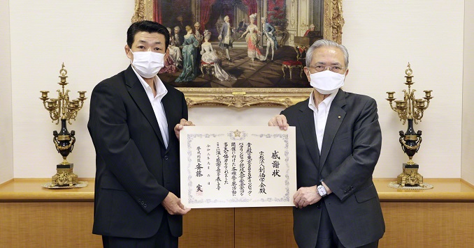 Two men pose with a large certificate