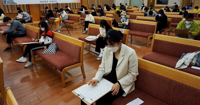 Participantes del examen sentados en una sala manteniendo el distanciamiento social