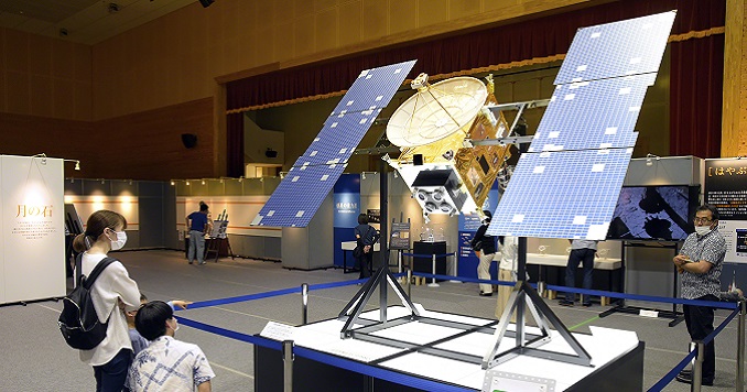 Exhibition visitors view a replica of a satellite.